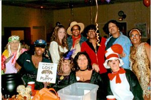 A group of female steelworkers in Halloween costumes smile at a party.