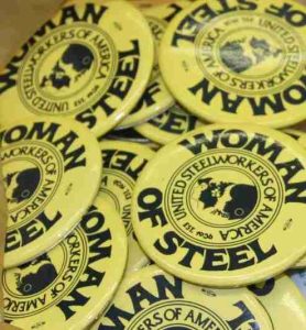 A stack of circular yellow buttons from the United Steelworkers of America's Women of Steel committee. 