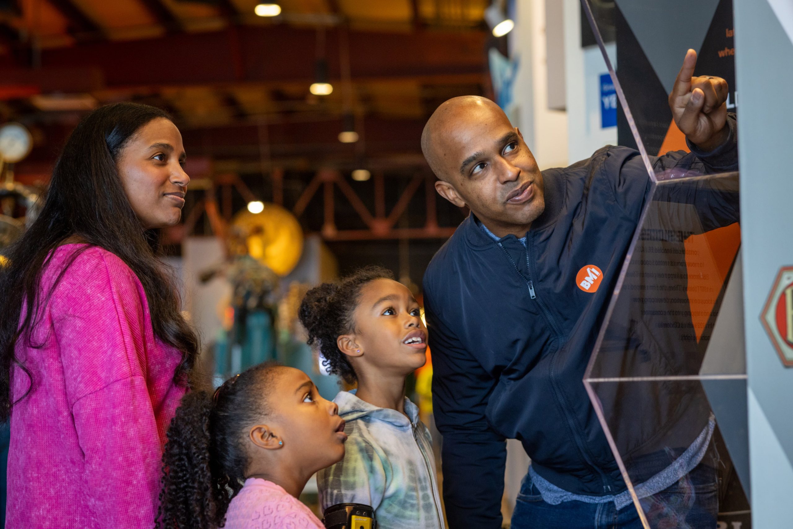 father pointing at an exhibit with his family