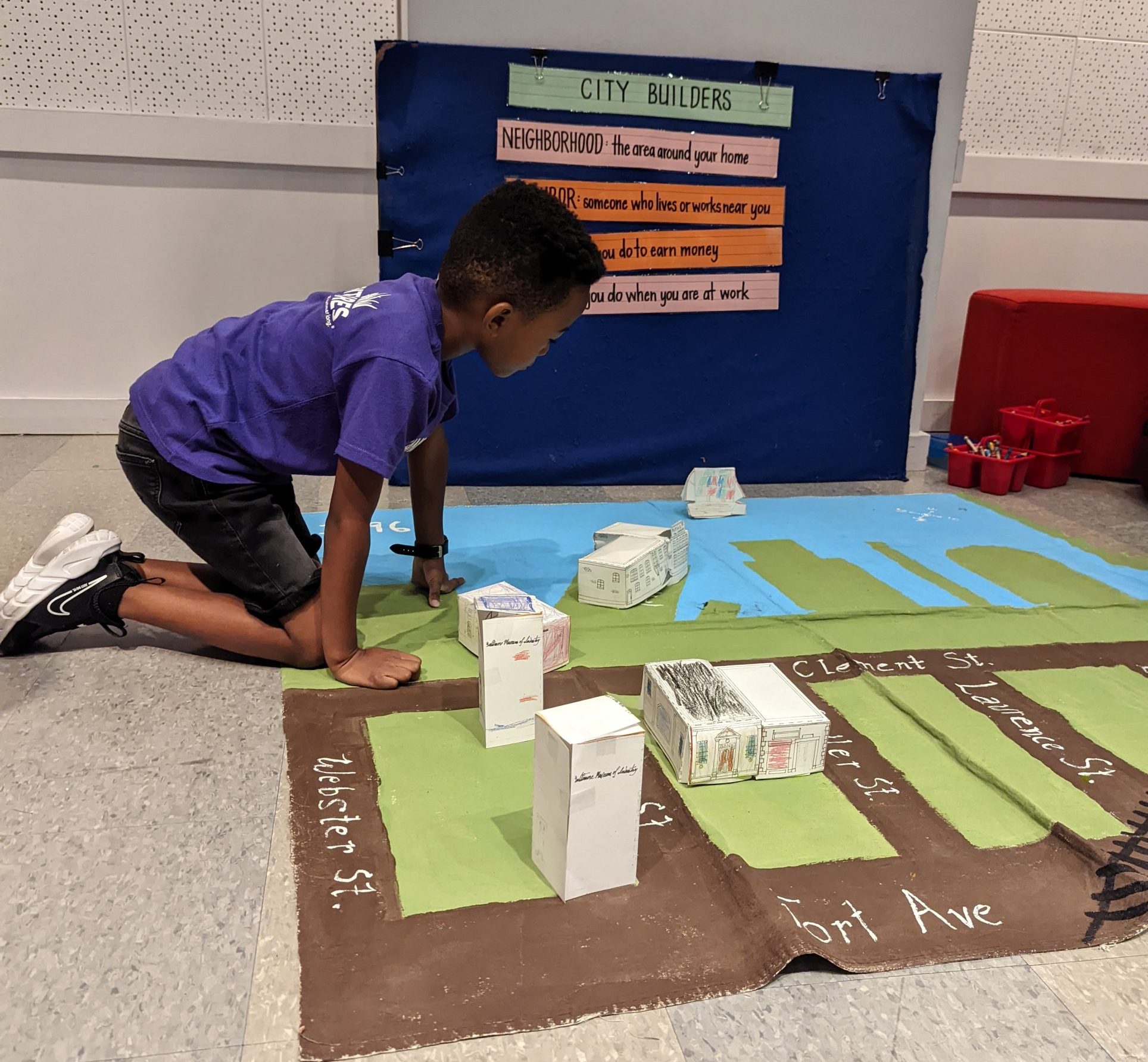 child builds small scale city out of paper