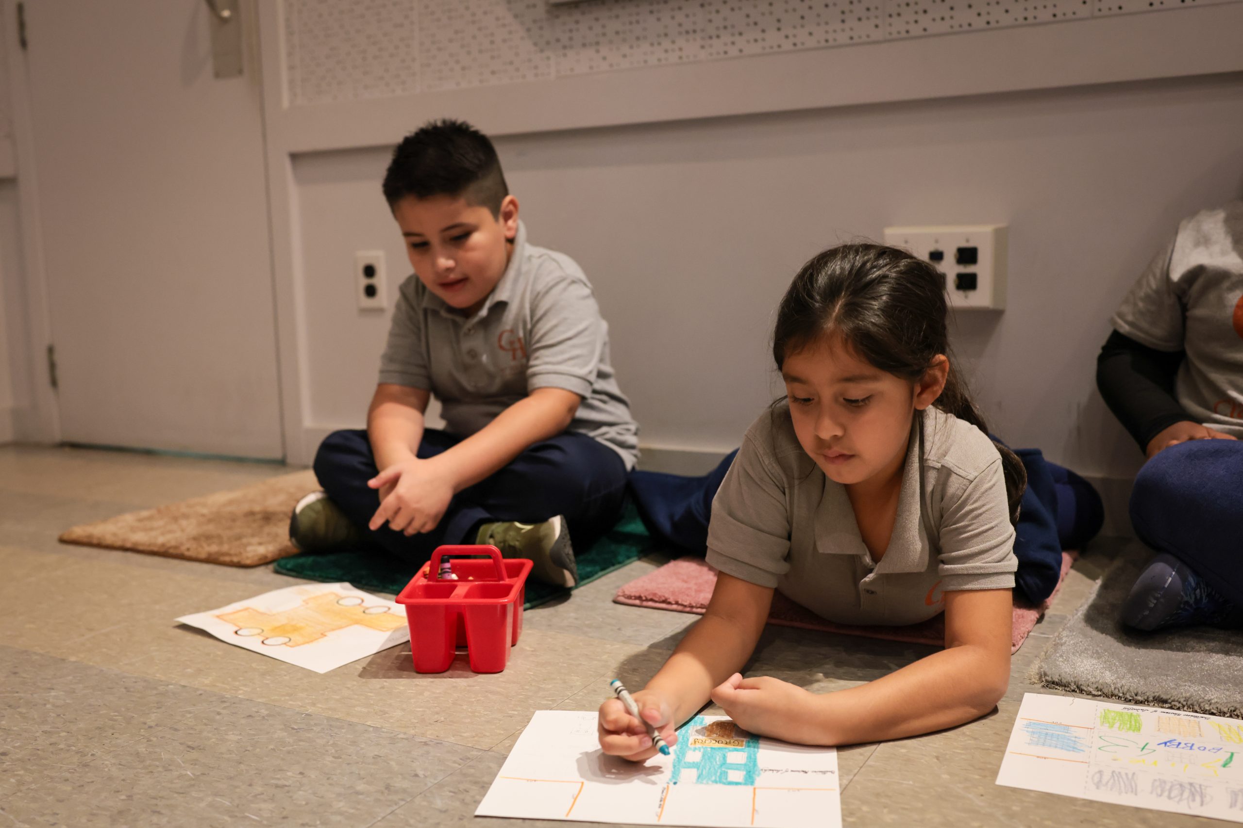 children sitting on floor drawing on paper